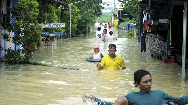 Warga melintasi banjir di Desa Laden Pamekasan, Jawa Timur, Sabtu (19/12/2020). [ANTARA FOTO/Saiful Bahri]