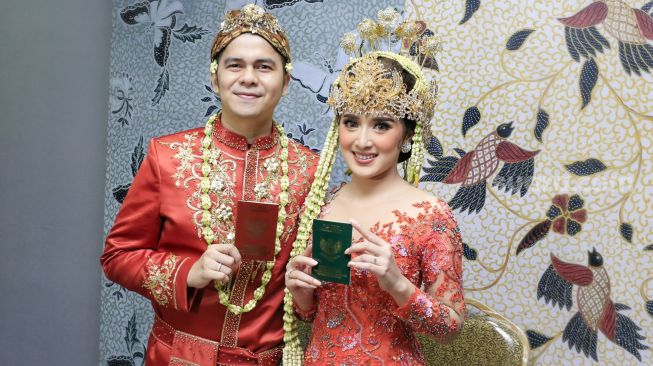 Aktor Handika Pratama dan istrinya, Rosiana Dewi menunjukkan buku nikah mereka usai melangsungkan pernikahan di Kawasan Kuningan, Jakarta Selatan, Minggu (20/12). [Suara.com/Alfian Winanto]