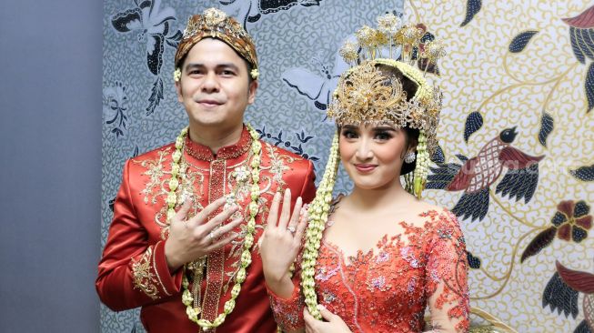 Aktor Handika Pratama dan istrinya, Rosiana Dewi menunjukkan cincin di jari manis mereka usai melangsungkan pernikahan di Kawasan Kuningan, Jakarta Selatan, Minggu (20/12). [Suara.com/Alfian Winanto]