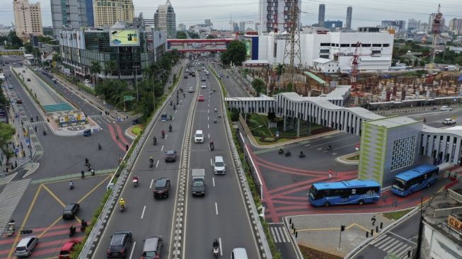 Foto udara sejumlah kendaraan melintas di kawasan Simpang Lima Senen, Jakarta, Selasa (15/12/2020). Pemprov DKI Jakarta telah merampungkan revitalisasi Simpang Lima Pasar Senen dengan menggunakan empat skala prioritas pembangunan transportasi berbasis jalan raya di Jakarta yaitu pejalan kaki, pesepeda/ kendaraan bebas emisi, angkutan umum serta kendaraan pribadi. [Suara.com/Angga Budhiyanto]
