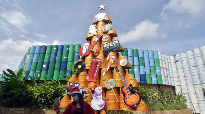 Pengunjung berswafoto dengan latar belakang pohon Natal berbahan drum bekas di Kebon Vintage Cars Bali, Denpasar, Bali, Sabtu (19/12/2020). ANTARA FOTO/Nyoman Hendra Wibowo