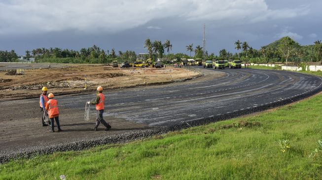 Sejumlah pekerja menyelesaikan pengerjaan pengaspalan lapisan atas badan jalan Mandalika MotoGP Street Circuit di The Mandalika, Pujut, Praya, Lombok Tengah, NTB, Minggu (20/12/2020). [ANTARA FOTO/Ahmad Subaidi]