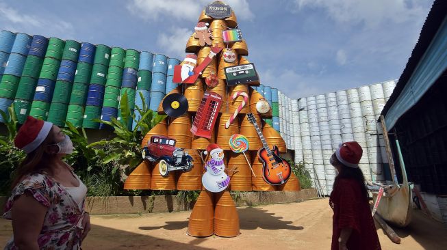 Pengunjung mengamati pohon Natal berbahan drum bekas di Kebon Vintage Cars Bali, Denpasar, Bali, Sabtu (19/12/2020).  [ANTARA FOTO/Nyoman Hendra Wibowo]