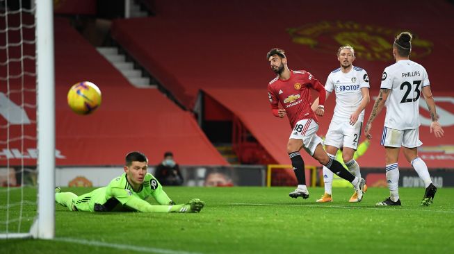 Gelandang Manchester United Bruno Fernandes (2L) mencetak gol ketiga timnya selama selama pertandingan sepak bola Liga Premier Inggris antara Manchester United melawan Leeds United di Old Trafford, Manchester, Inggris, Senin (20/12) dini hari WIB. 
Michael Regan / POOL / AFP