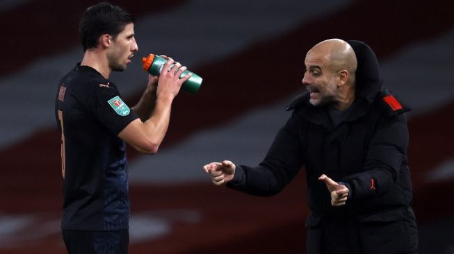 Manajer Manchester City, Pep Guardiola (kanan) menyampaikan instruksi pada bek Ruben Dias pada laga perempatfinal Piala Liga Inggris 2020/2021 kontra Arsenal di Emirates Stadium, London, Rabu (23/12/2020). [ADRIAN DENNIS / AFP]