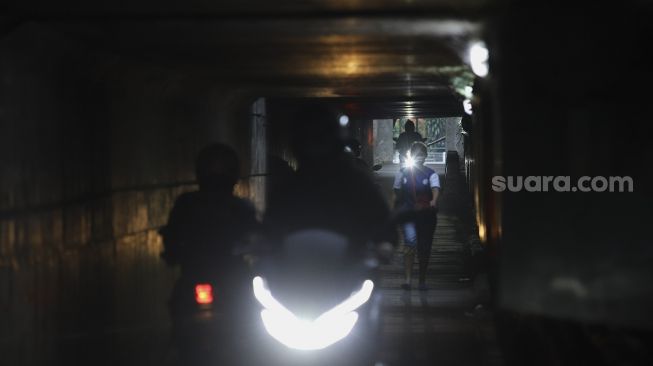 Seorang warga berjalan melintasi jalur alternatif di bawah kolong jalan tol Jagorawi di kawasan Terminal Kampung Rambutan, Jakarta, Rabu (23/12/2020). [Suara.com/Angga Budhiyanto]