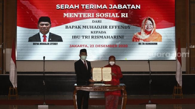 Menteri Koordinator Bidang Pembangunan Manusia dan Kebudayaan yang juga pejabat lama Menteri Sosial Ad Interim Muhajir Effendi (kiri) bersama Menteri Sosial Tri Rismaharini (kanan) menunjukan berkas berita acara serah terima jabatan Menteri Sosial di Kantor Kementerian Sosial, Jakarta, Rabu (23/12/2020). [Suara.com/Angga Budhiyanto]