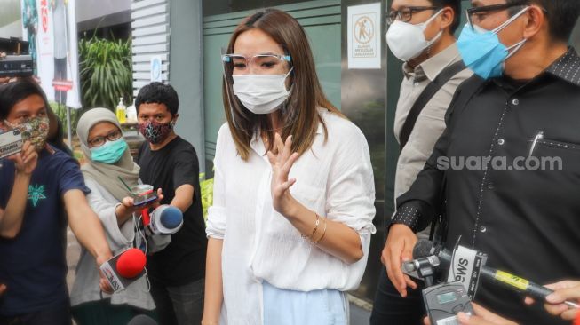 Penyanyi Gisella Anastasia menyapa awak media usai menjalani pemeriksaan terkait kasus video syur mirip dirinya di Gedung Reskrimsus Polda Metro Jaya, Jakarta Selatan, Rabu (23/12/2020). [Suara.com/Alfian Winanto]