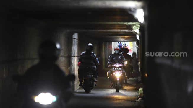 Sejumlah pengendara motor melintasi jalur alternatif di bawah kolong jalan tol Jagorawi di kawasan Terminal Kampung Rambutan, Jakarta, Rabu (23/12/2020). [Suara.com/Angga Budhiyanto]