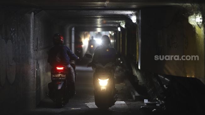 Sejumlah pengendara motor melintasi jalur alternatif di bawah kolong jalan tol Jagorawi di kawasan Terminal Kampung Rambutan, Jakarta, Rabu (23/12/2020). [Suara.com/Angga Budhiyanto]