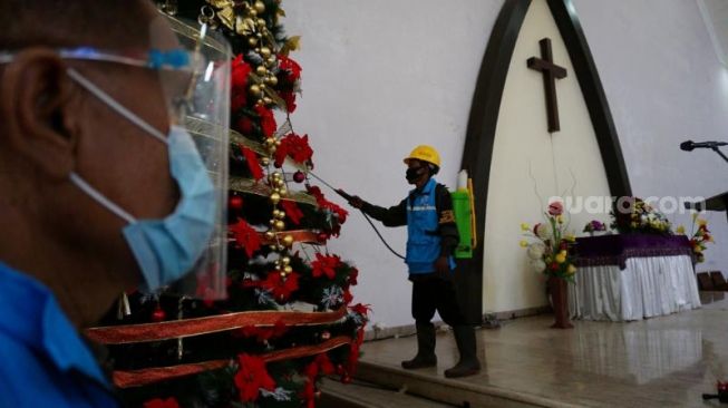 Petugas Gereja HKBP Ciputat melakukan penyemprotan disinfektan di area gereja sebelum pelaksanaan Misa Natal, Kamis (24/12/2020). [Suara.com/Hairul Alwan]