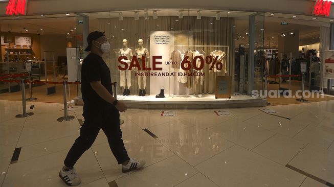 Pengunjung melintasi gerai pakaian yang memberikan potongan harga di Senayan City Mall, Jakarta, Jumat (25/12/2020). [Suara.com/Angga Budhiyanto]