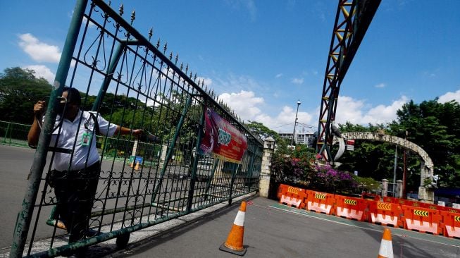 Petugas menutup gerbang masuk Taman Margasatwa Ragunan, Jakarta Selatan, Jumat (25/12/2020).]ANTARA FOTO/Sigid Kurniawan]