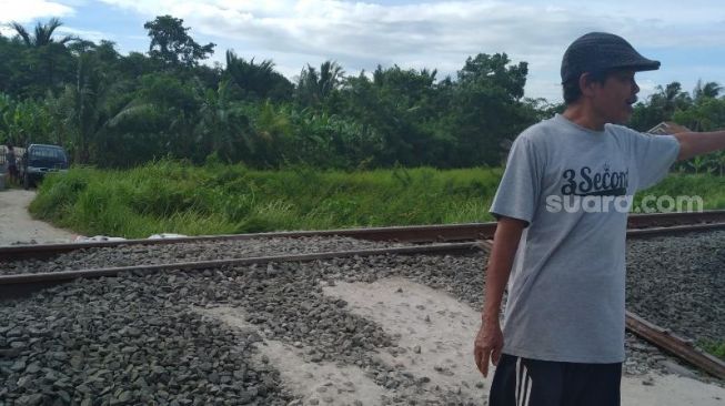 Salah satu warga menunjukkan kondisi jalur KA yang ditinggikan di Desa Bojong Pandan, Kabupaten Serang, Jumat (25/12/2020). [Suara.com/Feby Sahri Purnama]