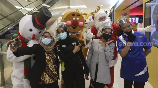 Pegawai berswafoto bersama petugas yang mengenakan kostum Santa Claus di Senayan City Mall, Jakarta, Jumat (25/12/2020). [Suara.com/Angga Budhiyanto]