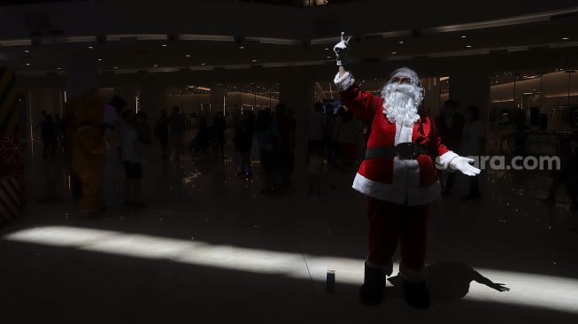 Petugas mengenakan kostum Santa Claus saat menghibur pengunjung di Senayan City Mall, Jakarta, Jumat (25/12/2020). [Suara.com/Angga Budhiyanto]