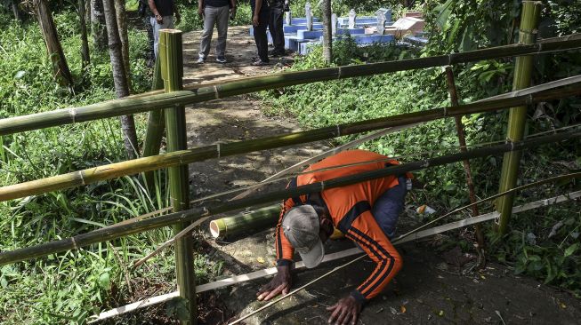 Warga menorobos pagar bambu menuju ke tempat pemakaman di Dusun Landeuh, Desa Sindangherang, Kabupaten Ciamis, Jawa Barat, Kamis (24/12/2020).  ANTARA FOTO/Adeng Bustomi
