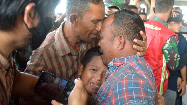 Keluarga nelayan (kiri) menyambut kedatangan salah seorang dari empat Anak Buah Kapal (ABK) KM Rajawalet 02 yang terdampar di Myanmar saat tiba di Pelabuhan Perikanan Samudera, Lampulo, Banda Aceh, Aceh, Jumat (25/12/2020).  [ANTARA FOTO/Ampelsa]
