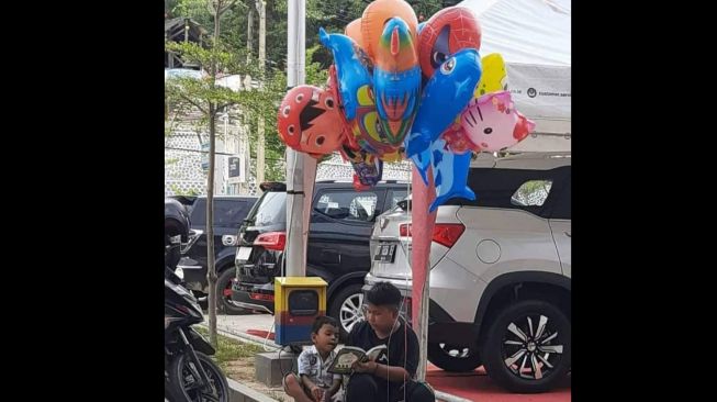 Terenyuh! Potret Bocah Mengajari Adik Baca Buku Iqro Sambil Jualan Balon