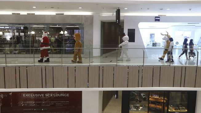 Petugas mengenakan kostum Santa Claus saat menghibur pengunjung di Senayan City Mall, Jakarta, Jumat (25/12/2020). [Suara.com/Angga Budhiyanto]