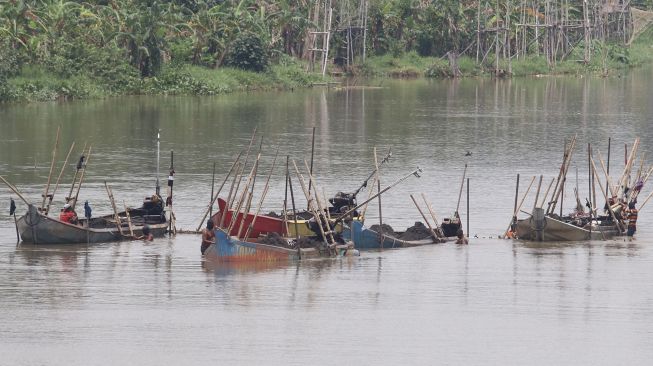 Pekerja menambang pasir menggunakan perahu di tengah aliran sungai Brantas, Kota Kediri, Jawa Timur, Senin (28/12/2020).  [ANTARA FOTO/Prasetia Fauzani]
