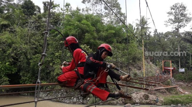 Relawan Vertical Rescue membuat jembatan gantung di yang menghubungkan Kampung Kihung dengan Kampung Batu Putuk, Bandar Lampung, Senin (28/12/2020). [Suara.com/Wakos Gautama]