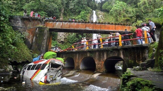 Warga menyaksikan sebuah minibus yang masuk ke sungai usai kecelakan beruntun di Kawasan Lembah Anai, Kabupaten Tanah Datar, Sumatera Barat, Rabu (30/12/2020).  ANTARA FOTO/Iggoy el Fitra