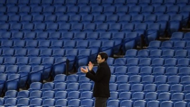 Gestur manajer Arsenal Mikel Arteta saat menyaksikan timnya berlaga menghadapi Brighton dalam pertandingan Liga Premier Inggris yang berlangsung di The American Express Stadium, Rabu (30/12/2020). [AFP]