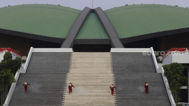 Petugas pemadam kebakaran menyemprotkan cairan disinfektan di area komplek Gedung DPR/MPR RI, Jakarta, Minggu (9/8/2020). [Suara.com/Angga Budhiyanto]