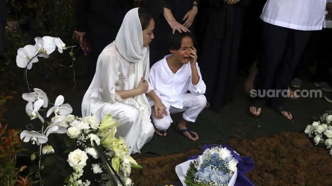 Ekspresi Bunga Citra Lestari beserta anaknya Noah Sinclair saat prosesi pemakaman Ashraf Sinclair di kompleks pemakaman San Diego Hills, Karawang, Jawa Barat, Selasa (18/2/2020). [Suara.com/Angga Budhiyanto]