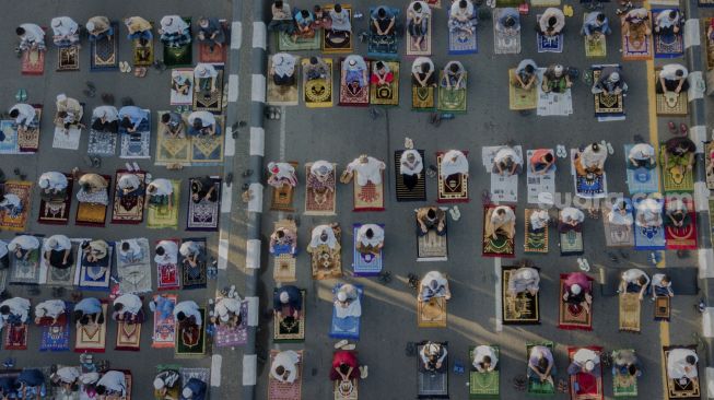 Foto udara Umat Islam melaksanakan shalat Idul Fitri 1 Syawal 1441 Hijriah secara berjamaah di ruas Jalan Jenderal Sudirman, Kranji, Bekasi, Jawa Barat, Minggu (24/5). [Suara.com/Angga Budhiyanto]