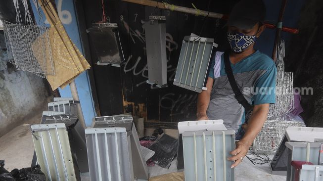 Pedagang alat panggang menata dagangannya di kawasan Pasar Minggu, Jakarta, Kamis (31/12/2020). [Suara.com/Angga Budhiyanto]