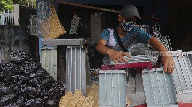 Pedagang alat panggang menata dagangannya di kawasan Pasar Minggu, Jakarta, Kamis (31/12/2020). [Suara.com/Angga Budhiyanto]