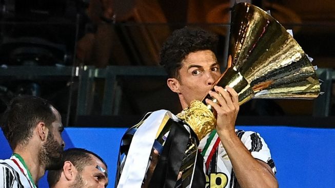 Megabintang Juventus, Cristiano Ronaldo mencium trofi Liga Italia setelah timnya jadi kampiun di musim 2019/2020. [Isabella BONOTTO / AFP]
