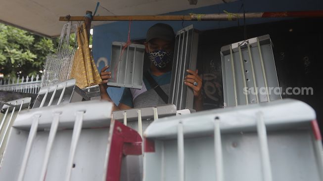 Pedagang alat panggang menata dagangannya di kawasan Pasar Minggu, Jakarta, Kamis (31/12/2020). [Suara.com/Angga Budhiyanto]