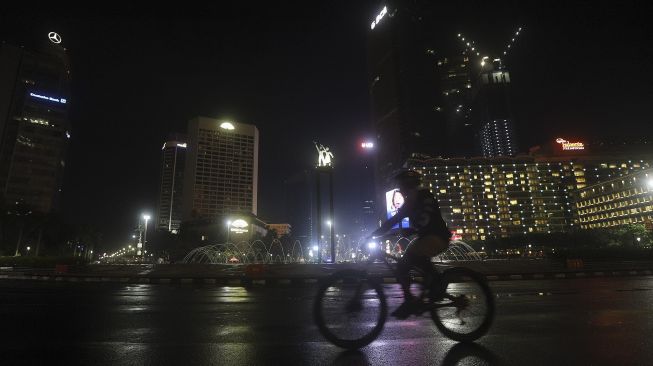 Warga bersepeda saat diberlakukannya Car Free Night (malam bebas kendaraan) dan Crowd Free Night (malam bebas keramaian) pada malam pergantian tahun di kawasan Bundaran HI, Jakarta, Kamis (31/12/2020). [Suara.com/Angga Budhiyanto]