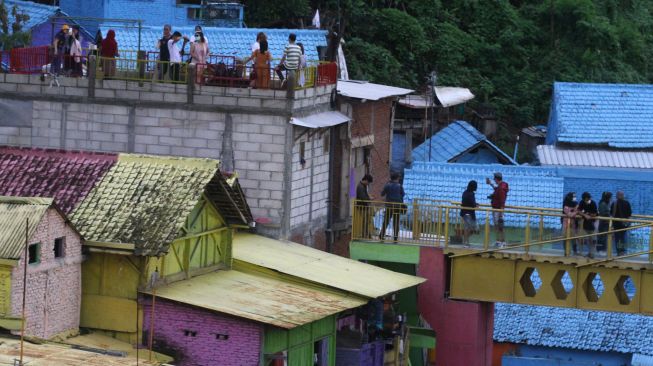 Wisatawan memanfaatkan libur tahun baru dengan berekreasi di Kampung Warna-Warni Jodipan, Malang, Jawa Timur, Jumat (1/1/2021). ANTARA FOTO/Ari Bowo Sucipto
