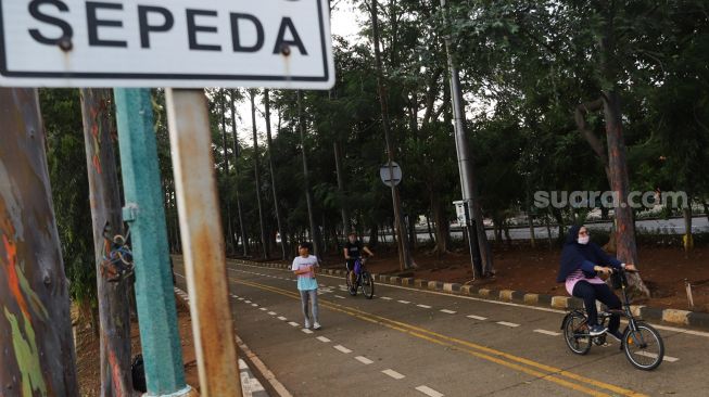 Warga berolahraga di kawasan Banjir Kanal Timur (BKT), Jakarta Timur, Jumat (1/1/2020). [Suara.com/Alfian Winanto]