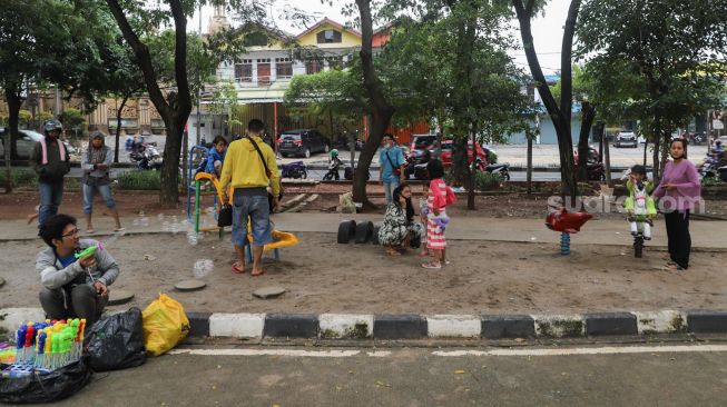 Anak - anak bermain di kawasan Banjir Kanal Timur (BKT), Jakarta Timur, Jumat (1/1/2020). [Suara.com/Alfian Winanto]