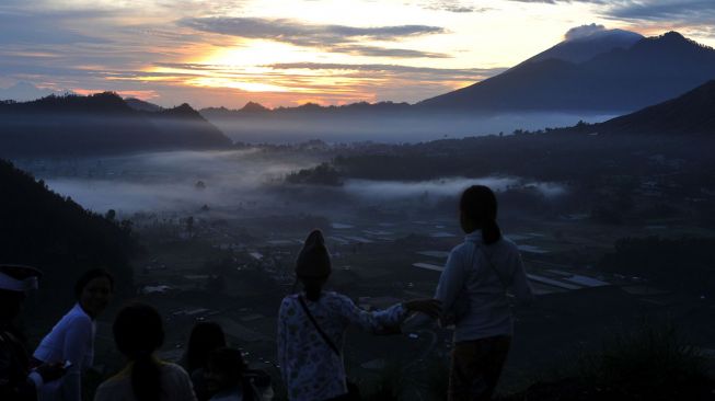 Wisatawan menyaksikan matahari terbit pertama tahun 2021 di Desa Pinggan, Kintamani, Bangli, Bali, Jumat (1/1/2021).  [ANTARA FOTO/Fikri Yusuf]