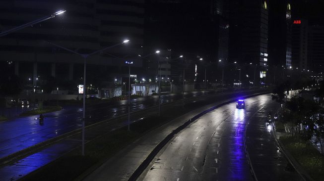 Petugas kepolisian melaksanakan patroli  saat diberlakukannya Car Free Night (malam bebas kendaraan) dan Crowd Free Night (malam bebas keramaian) pada malam pergantian tahun di Jalan Sudirman, Jakarta, Kamis (31/12/2020). [Suara.com/Angga Budhiyanto]