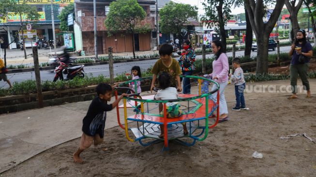 Anak - anak bermain di kawasan Banjir Kanal Timur (BKT), Jakarta Timur, Jumat (1/1/2020). [Suara.com/Alfian Winanto]