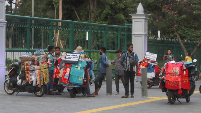 Beberapa pedagang nekat berjualan di trotoar belakang Monumen Nasional atau Monas di Jakarta Pusat, Sabtu (2/1/2021). [Suara.com/Alfian Winanto]