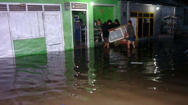 Sejumlah warga menyelamatkan barang-barang saat rumahnya tergenang banjir di Desa Tembok Lor, Kabupaten Tegal, Jawa Tengah, Jumat (1/1/2021) malam. ANTARA FOTO/Oky Lukmansyah