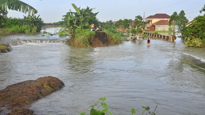 Warga menyaksikan kondisi tanggul Sungai Gelis yang jebol di Desa Setrokalangan, Kudus, Jawa Tengah, Minggu (3/1/2021). [ANTARA FOTO/Yusuf Nugroho]