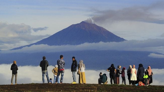 Pengunjung berada di tempat wisata Bukit Tirai Embun dengan latar Gunung Kerinci, Jambi, Minggu (3/1/2021). [ANTARA FOTO/Wahdi Septiawan]