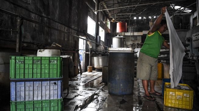 Pekerja menyuci kain penyaring saat menggelar aksi mogok berproduksi di salah satu pabrik tahu di Jakarta, Sabtu (2/1/2021). [ANTARA FOTO/Hafidz Mubarak A]