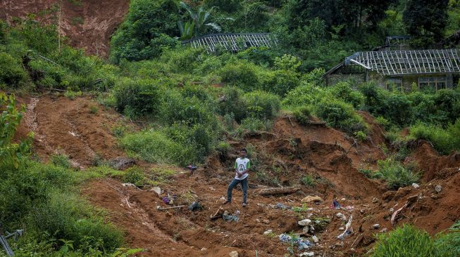 Seorang warga berdiri di atas bangunan rumah yang tertimbun material longsor di Kampung Cigobang, Lebak, Banten, Minggu (3/1/2021). [ANTARA FOTO/Muhammad Bagus Khoirunas]