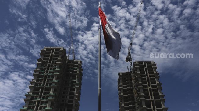 Pekerja dengan menggunakan alat berat menyelesaikan pembangunan gedung bertingkat di kawasan Ampera, Jakarta, Selasa (5/1/2021). [Suara.com/Angga Budhiyanto]