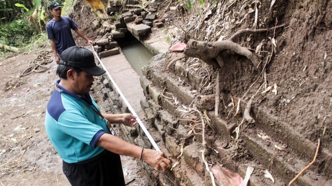 Petugas Balai Pelestarian Cagar Budaya (BPCB) Trowulan mengukur struktur bata kuno yang ditemukan warga di Dusun Blimbing, Desa Bulusari, Gempol, Pasuruan, Jawa Timur, Selasa (5/1/2021). ANTARA FOTO/Umarul Faruq
